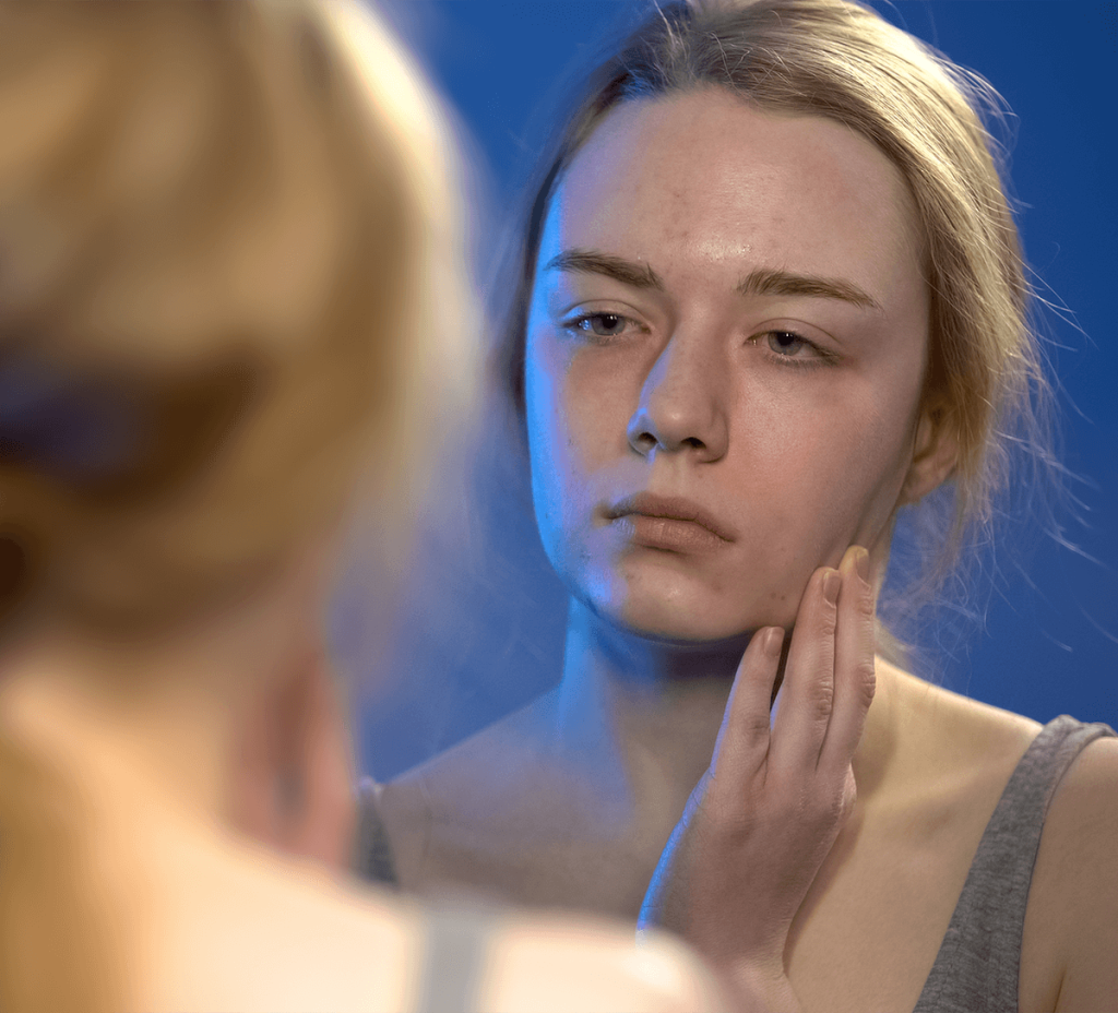 Young woman looking sad in mirror