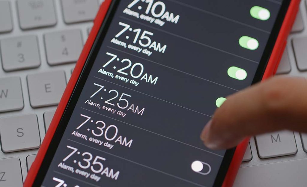 Person setting alarm clock on phone