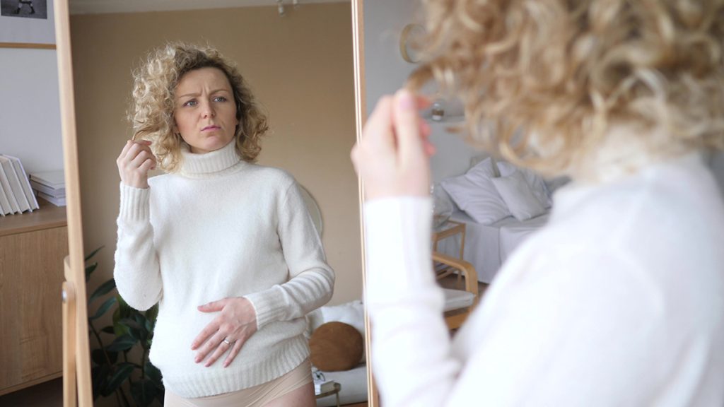 Upset Pregnant Woman Looking In Mirror
