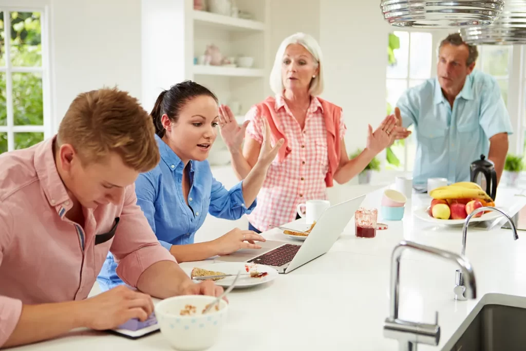 Woman holding her hand out in a stop sign as family is having a dispute over breakfast.