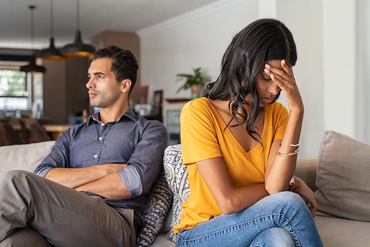 A couple sitting a couch looking away from each other after a fight.