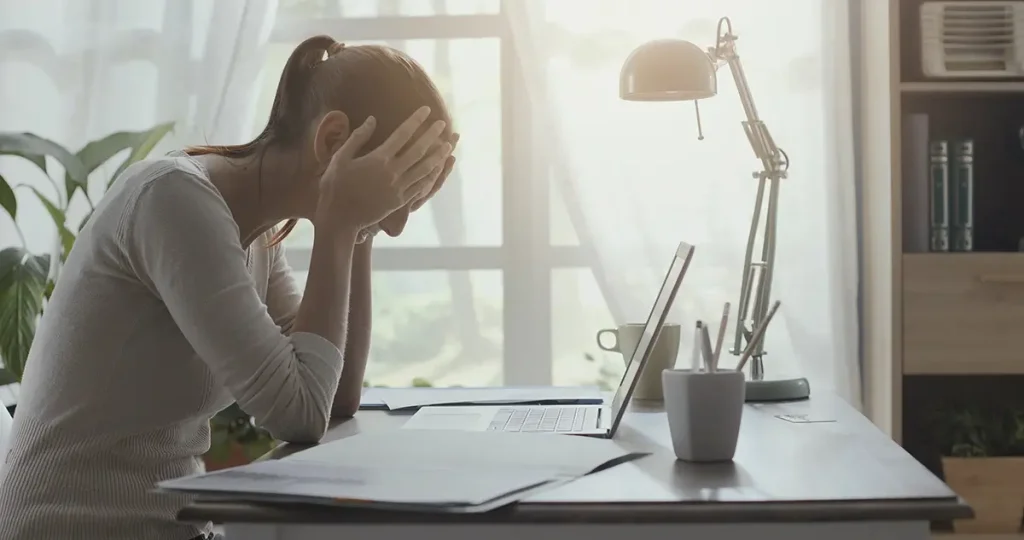 Woman at desk with head in hands
