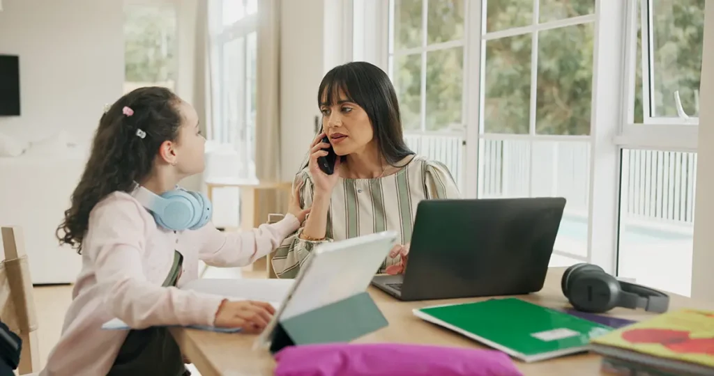 Working mom on the phone while her child asks her a question.