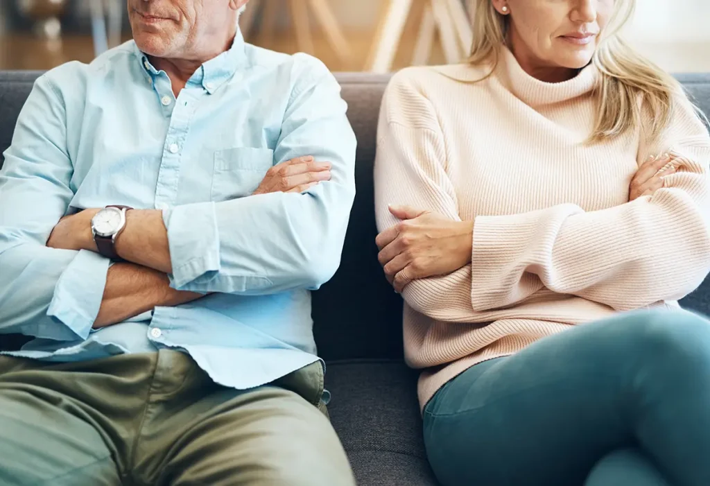 Couple with arms crossed, in a conflict on the couch